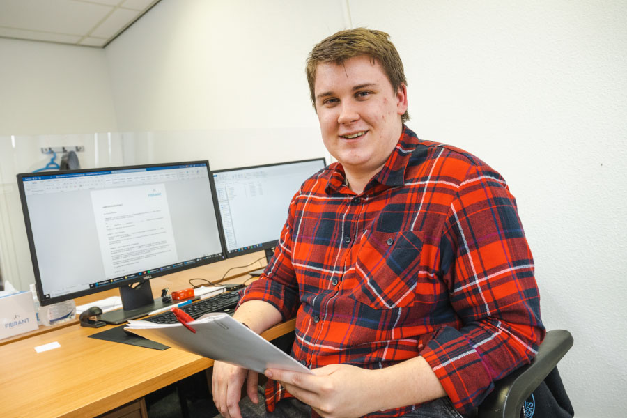 Een jongen zit lachend achter zijn computer